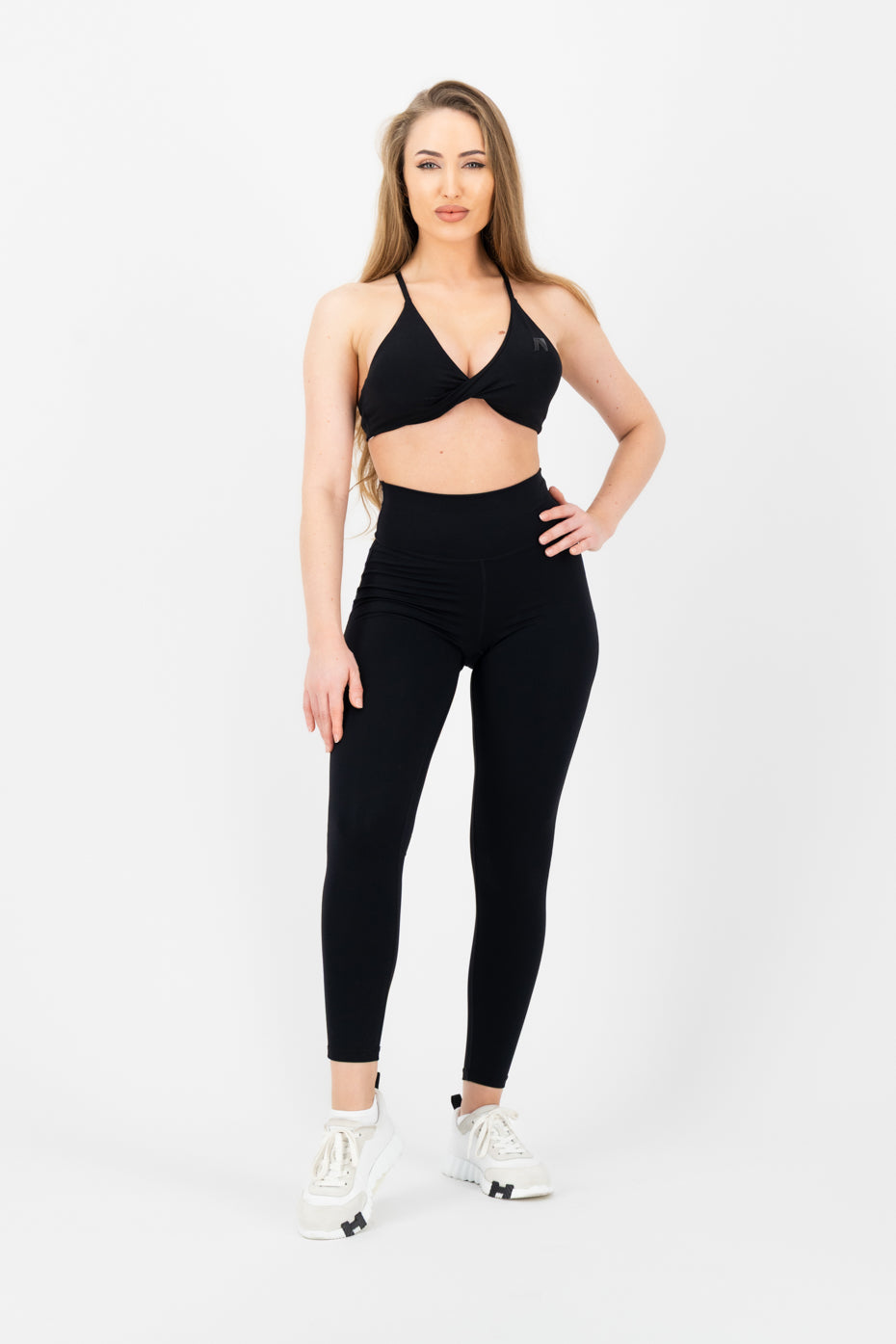 Woman wearing a black sports bra and leggings on a white background