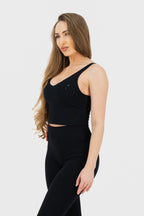 Woman wearing a black sleeveless top and pants on a white background