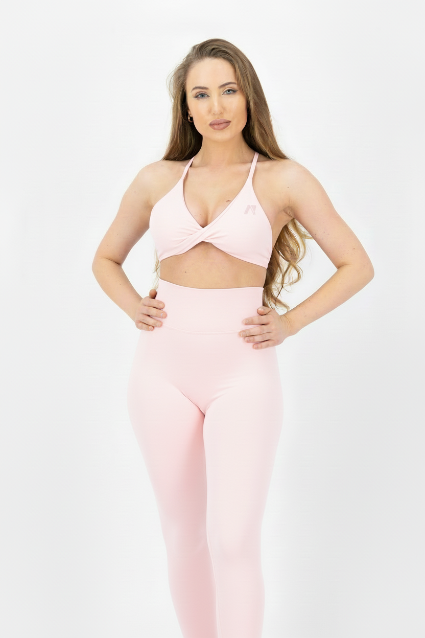Woman wearing a pink sports bra and leggings on a white background