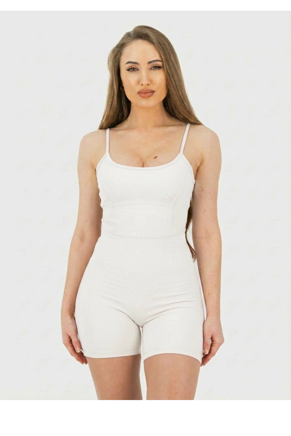Woman wearing a white bodysuit against a plain background